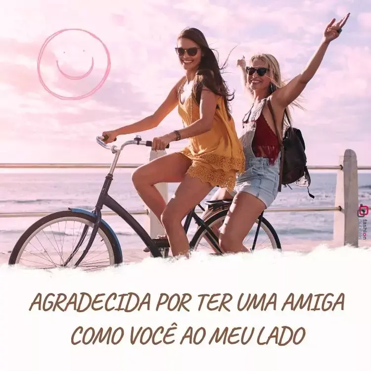 Imagem de duas amigas em uma bicicleta com um mar ao fundo. Ambas estão usando óculos de sol e sorrindo. A que conduz a bibicleta está usando uma roupa amarela e a outra está de braços abertos atrás usando jardineira jeans e blusa vermelha. Embaixo, há um bloco branco com escrito em marrom "Agradecida por ter uma amiga como você ao meu lado"