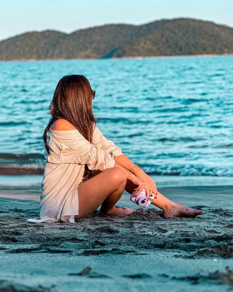 mulher sentada na areia da praia