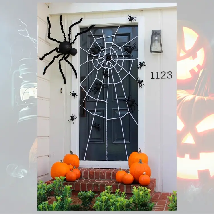 Entrada de casa com parede branca, porta preta com aranhas de plástico e teia de barbante, além de abóboras na escada 