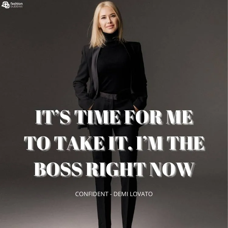 Mulher loira de pele clara, usando conjunto de roupa preta em um fundo cinza. Ainda, há o trecho ""It’s time for me to take it. I’m the boss right now" e "Confident - Demi Lovato"