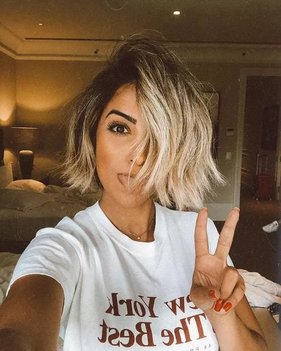 Menina com corte de cabelo curto fazendo sinal de paz e amor e mostrando a lingua