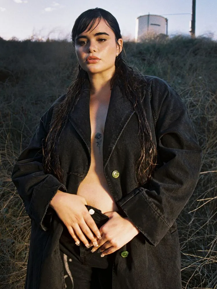Barbie Ferreira posa com um casaco longo preto sem nada por baixo.