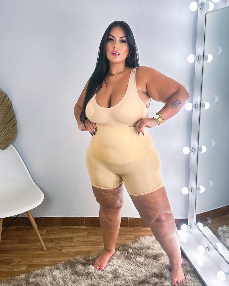 Mulher com lipedema usando roupa que aperta e desfarça gordurinhas, em local com espelho