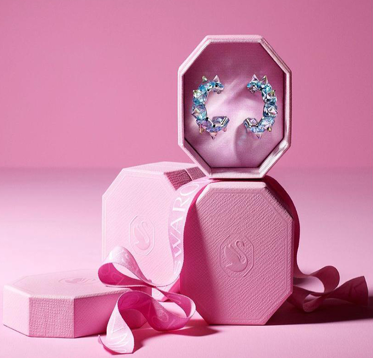 Brincos de cristal azul guardados em uma caixa de formato octogonal rosa.