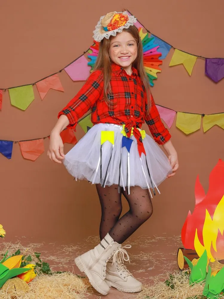 Menina de pele clara com camisa xadrez vermelha, saia de tule e adereços juninos 
