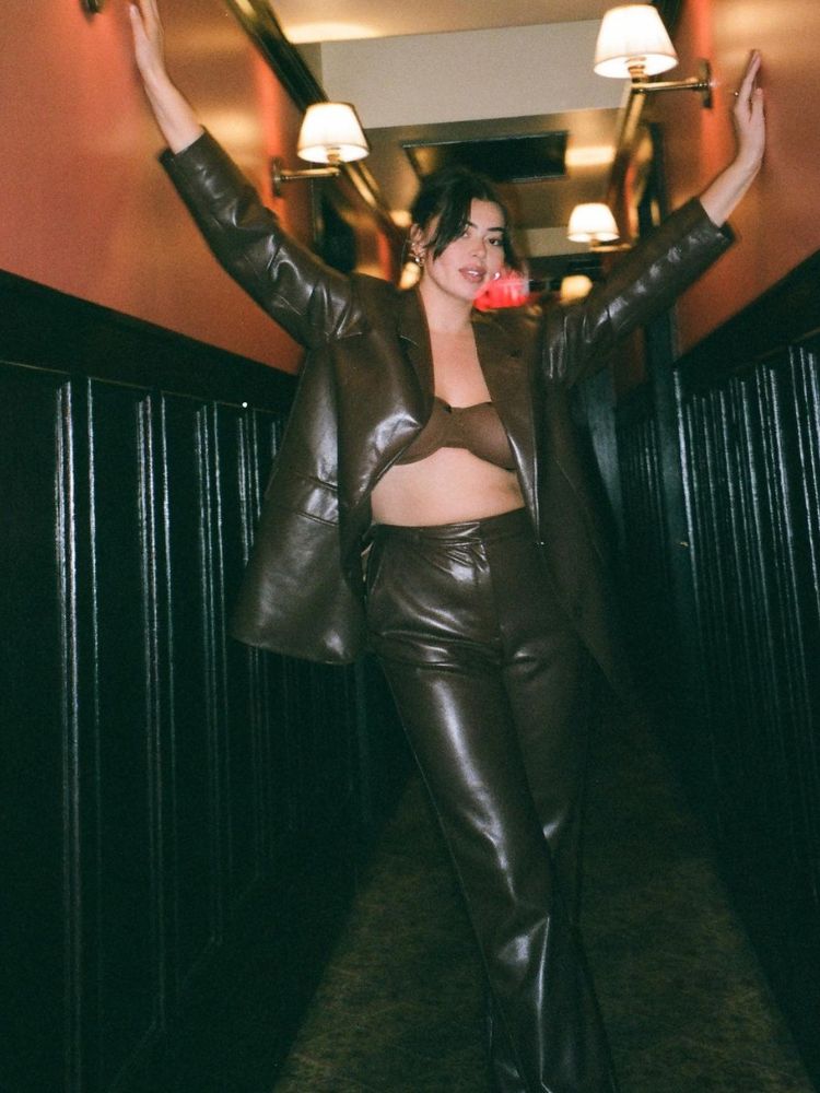 mulher usando conjunto de blazer e calça de couro marrom com sutiã da mesma cor
