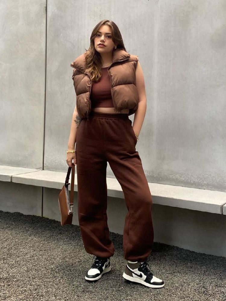 foto de mulher usando regata marrom, colete puffer, calça de moletom e tênis Nike