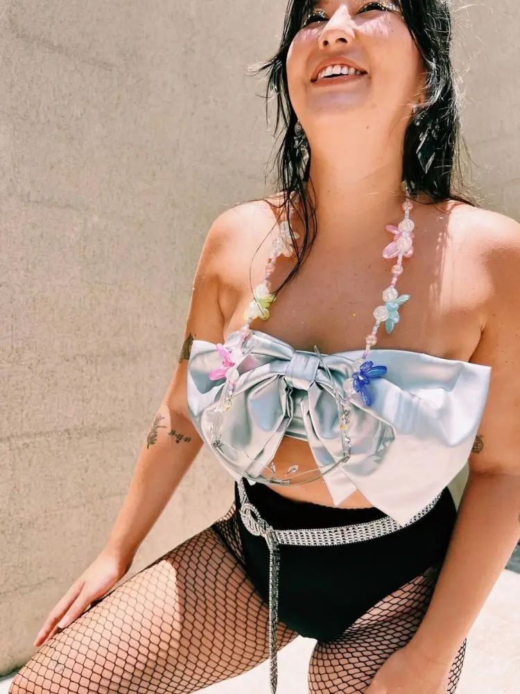 foto de mulher usando top de laço prata, hot pant preta e meia-calça arrastão no Carnaval e colar de miçanga
