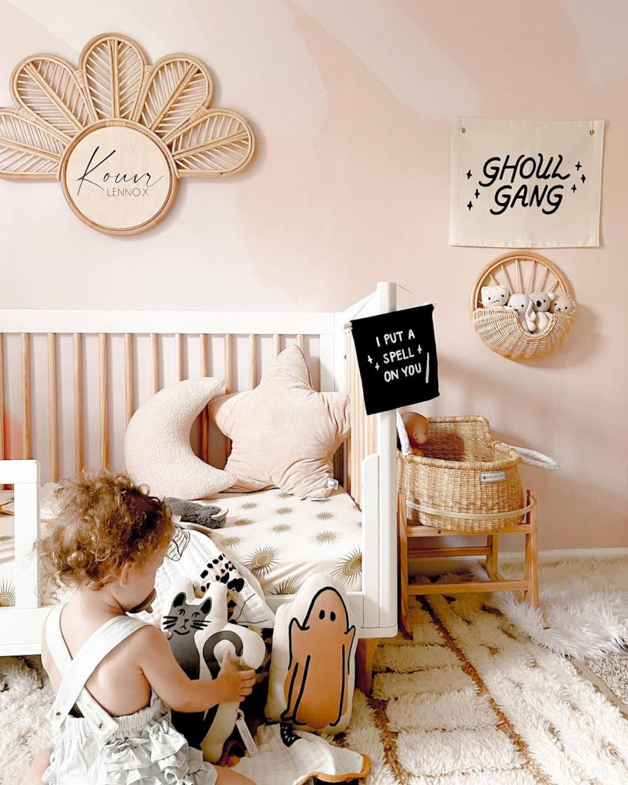 Quarto infantil com criança brincando com almofadas no tema Halloween