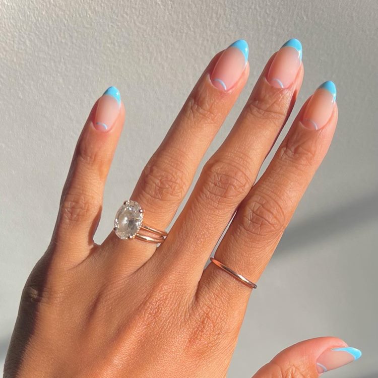 Unhas decoradas em tons de azul com francesinha e na cutícula
