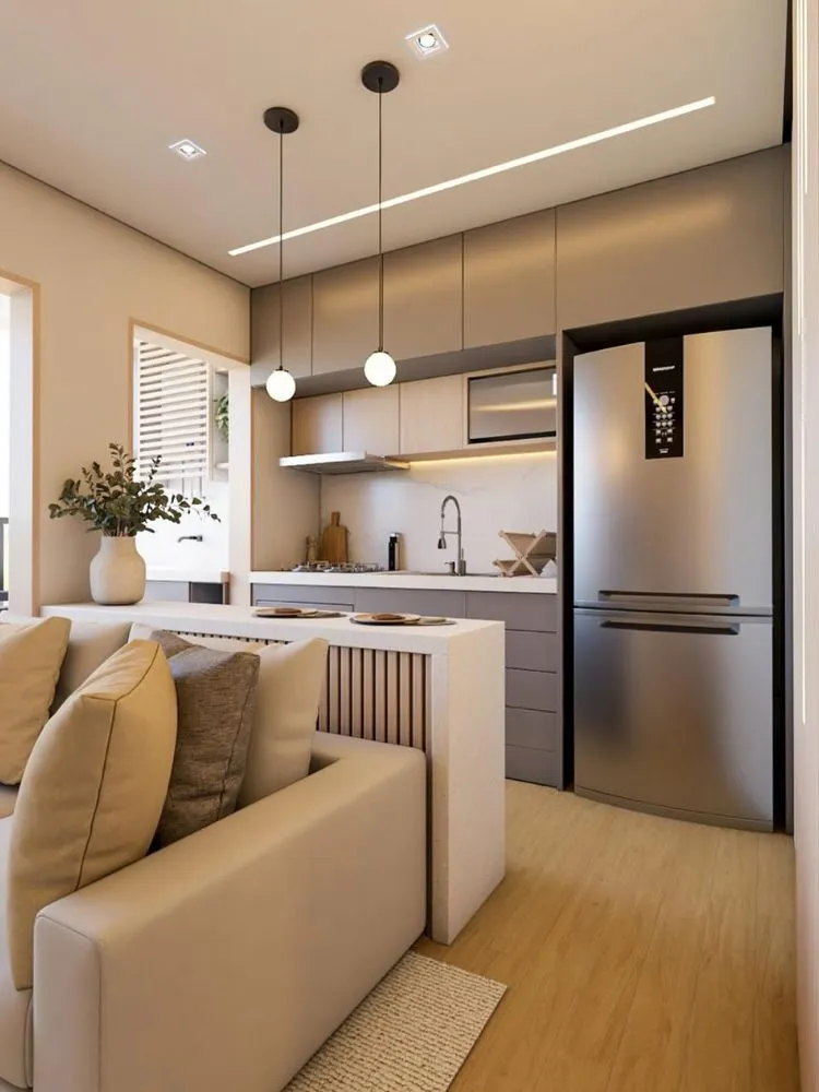 Sala integrada com cozinha, ambas em tons claros e madeira, com pendente sobre bancada de alimentação
