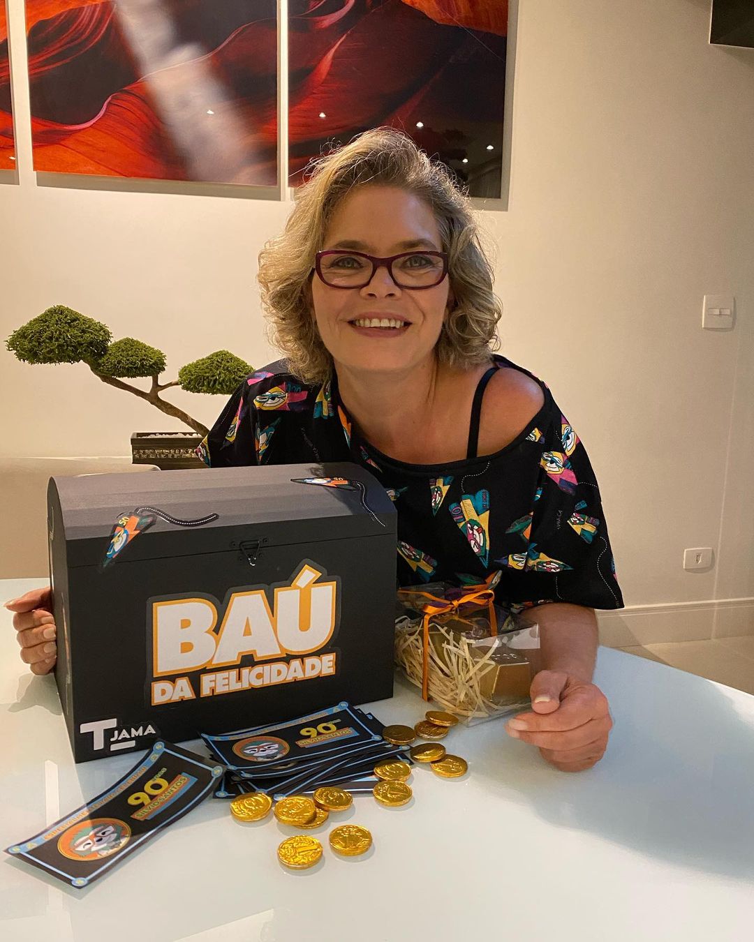Cintia abravanel em mesa com uma caixa (baú) da felicidadade