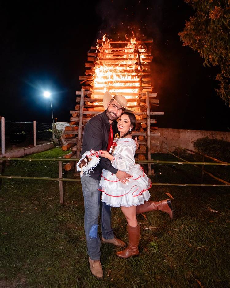 Casal de noivos caipira em frente a uma fogueira alta