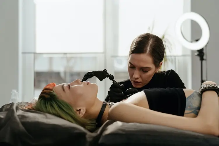 mulher deitada em maca sendo tatuada