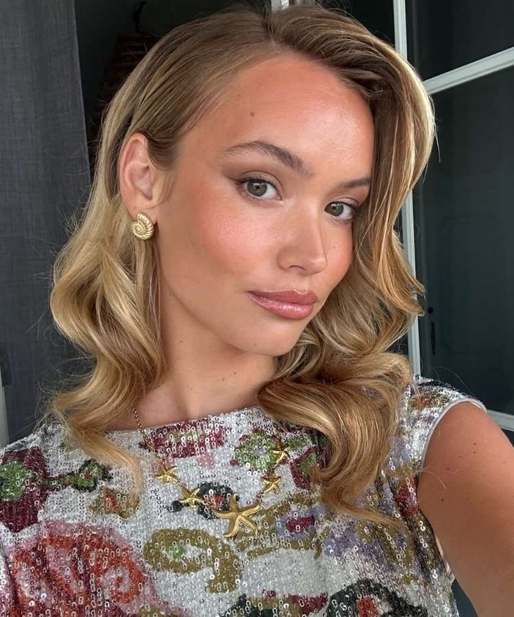 Mulher loira usando maquiagem de Natal básica iluminada com gloss