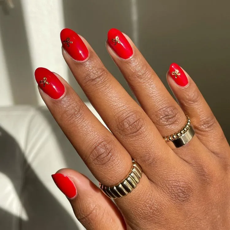 Unhas redondas com pequenos laços dourados 
