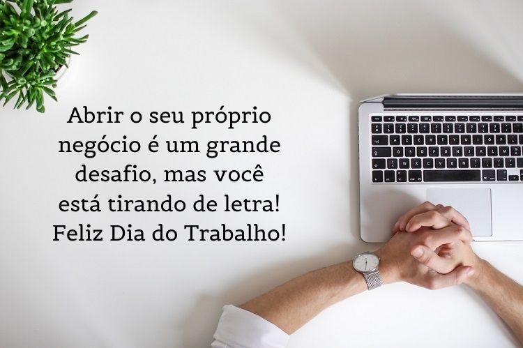 Foto de braço de homem de pele clara, computador e planta, com a frase "brir o seu próprio negócio é um grande desafio, mas você está tirando de letra! Feliz Dia do Trabalho!"