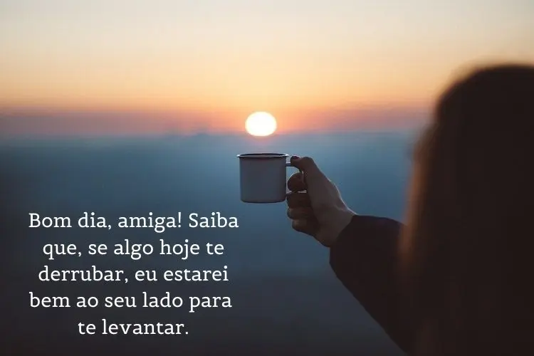Foto de pessoa erguendo xícara em direação ao nascer do sol e frase: Bom dia, amigo(a)! Saiba que, se algo hoje te derrubar, eu estarei bem ao seu lado para te levantar.