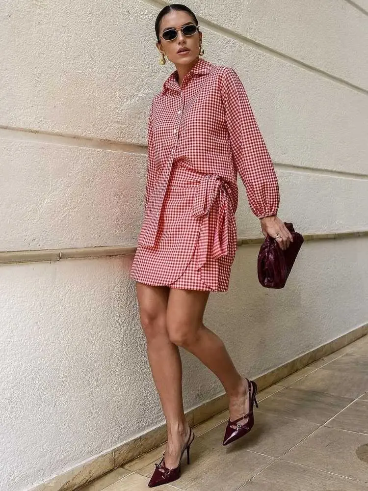 Mulher de pele clara usando camisa e saia em xadrez vichy branco e vermelho