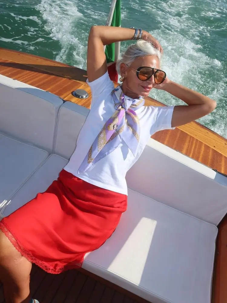 mulher usando lenço, camiseta branca e saia vermelha com renda