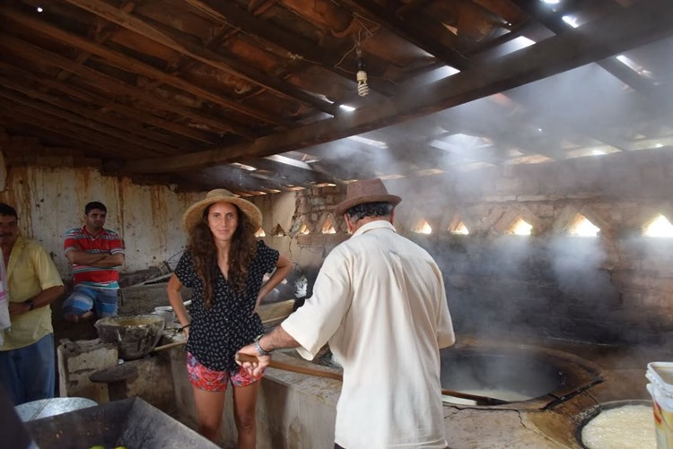 Influenciadora Júlia Tolezano com chapéu de palha, em casa rústica, ao lado de outras pessoas cozinhando algo