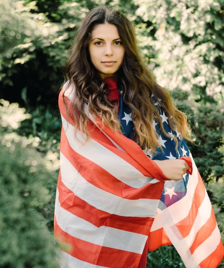 Foto de mulher morena enrolada em bandeira dos Estados Unidos