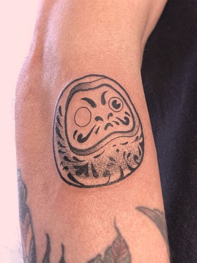 tatuagem de daruma feita próximo ao cotovelo. 