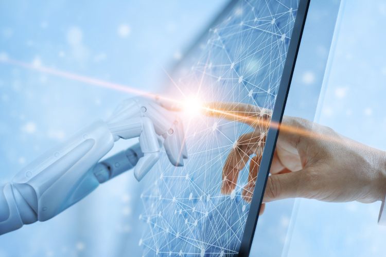 Mão robótica e humana se conectam através de uma tela interativa iluminada por um brilho de lente, simbolizando colaboração entre inteligência artificial e humanos. A imagem reflete inovação tecnológica e tendências de publicidade para 2025 em um mundo digital integrado.