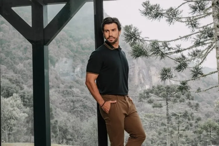Foto do cantor sertanejo Mariano usando look da sua coleção com a DLZ: camisa polo preta e calça marrom