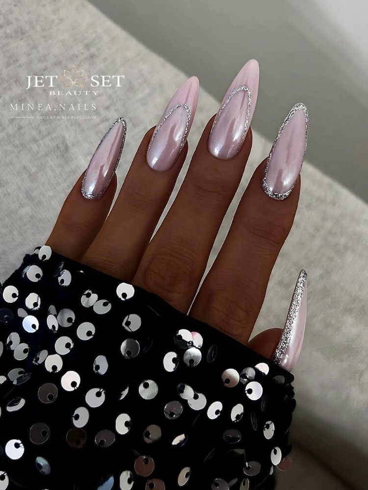 Pessoa de pele negra com unhas longas almond usando esmalte cromado rosa claro e nail art em prata 