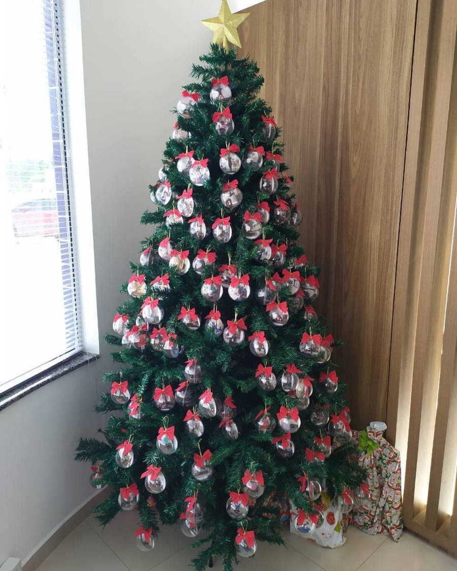 Bolas de natal com fotos dentro e laços em cima.