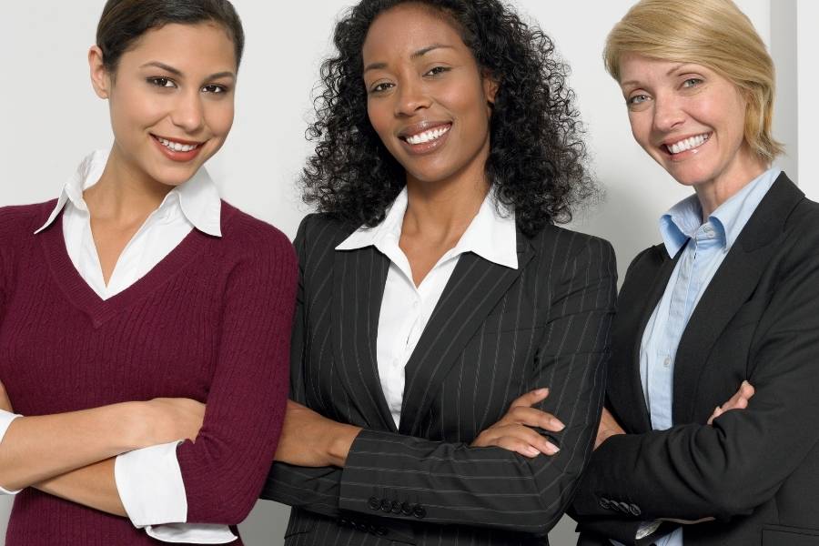 Três mulheres com roupas sociais de braços cruzados mostrando a participação feminina na política.