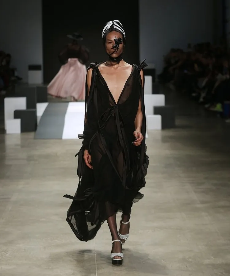 Foto de modelo na passarela usando vestido longo preto