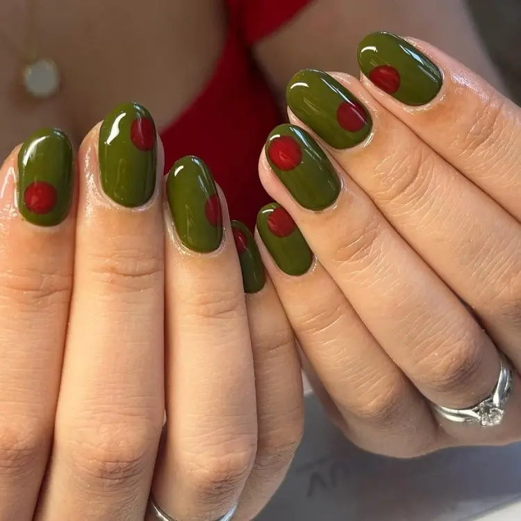 Mãos com unhas curtas e redondas em verde oliva com pontos vermelhos 