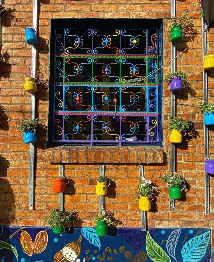 Jardim suspenso colorido em parede de tijolo ao redor de janela