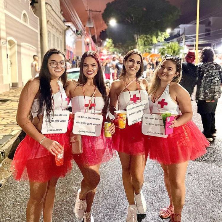 Quatro amigas fantasiadas de salva-vidas com plaquinha "me deixa salvar uma das suas sete vidas?"