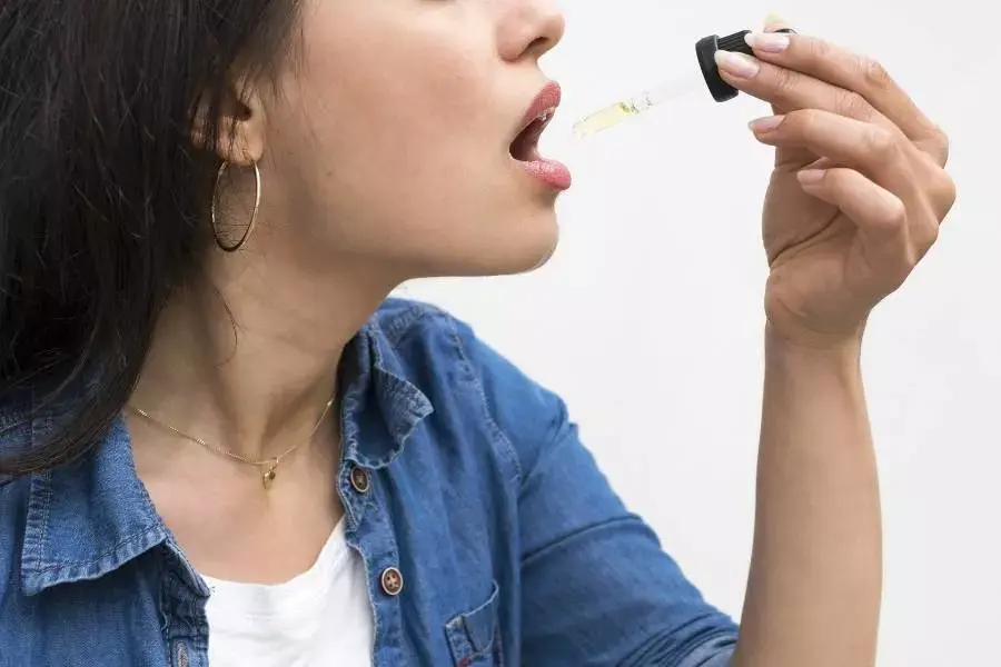 Mulher tomando óleo de canabidiol em conta-gotas.