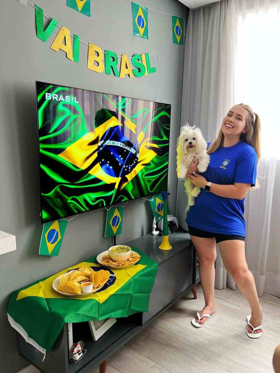 Foto de mulher usando camiseta azul do Brasil com short preto e chinelo.