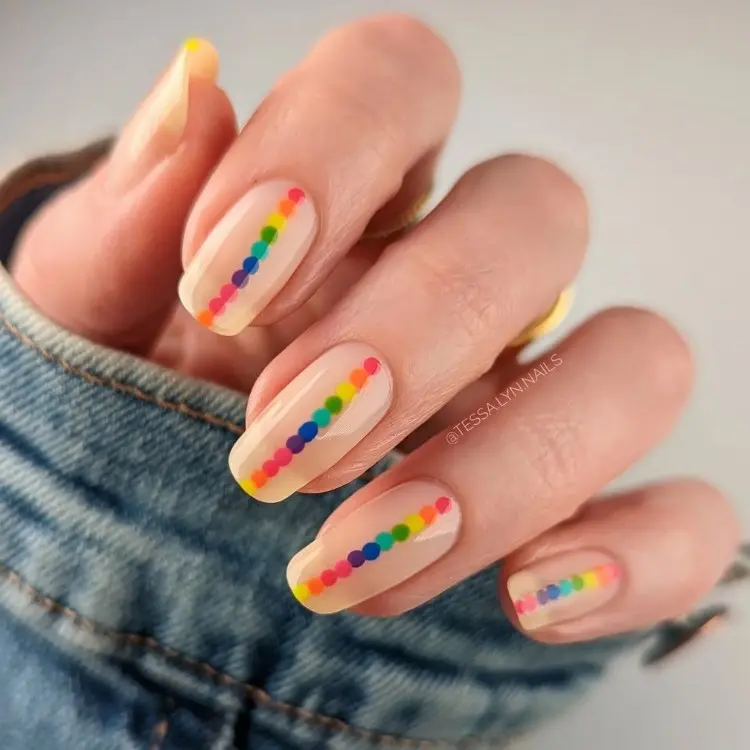 Unhas nudes com faixa central vertical de bolinhas coloridas