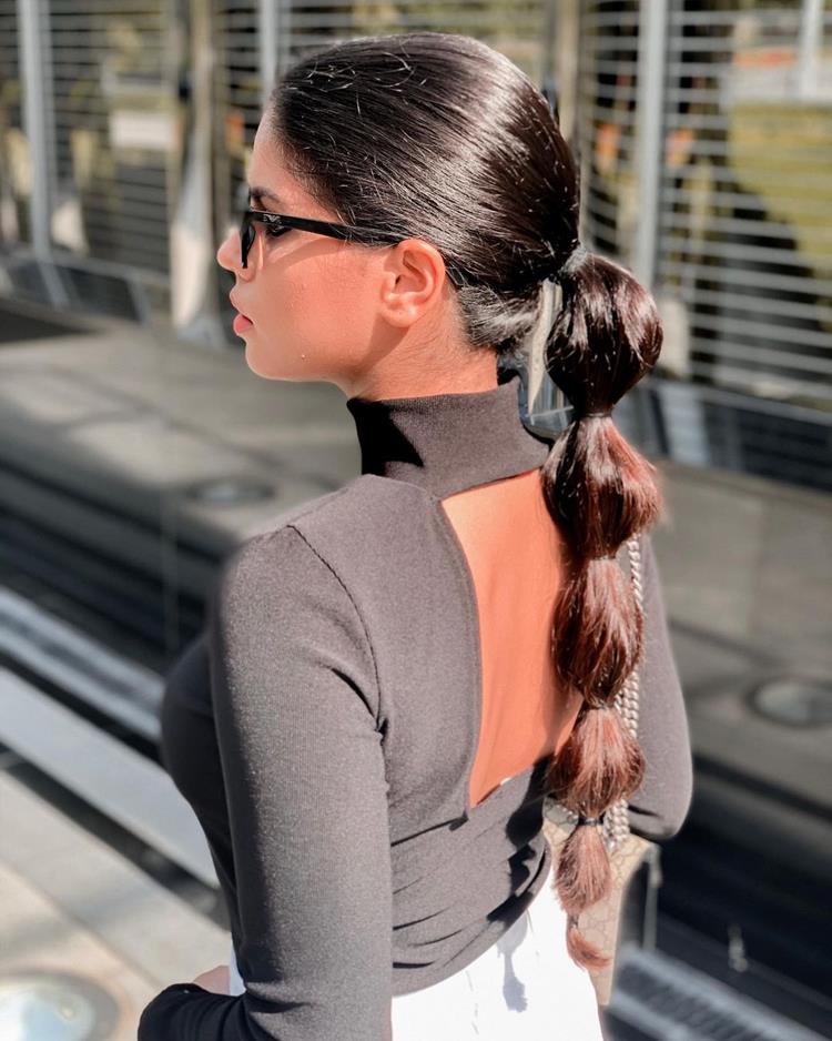 mulher de costas com cabelocastanho liso preso em penteado de trança de bolhas