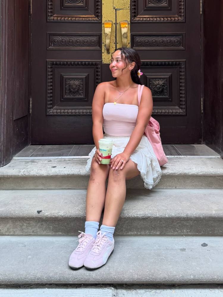 Mulher de pele clara usando top rosa, saia fluida de renda e speedcatat rosa 