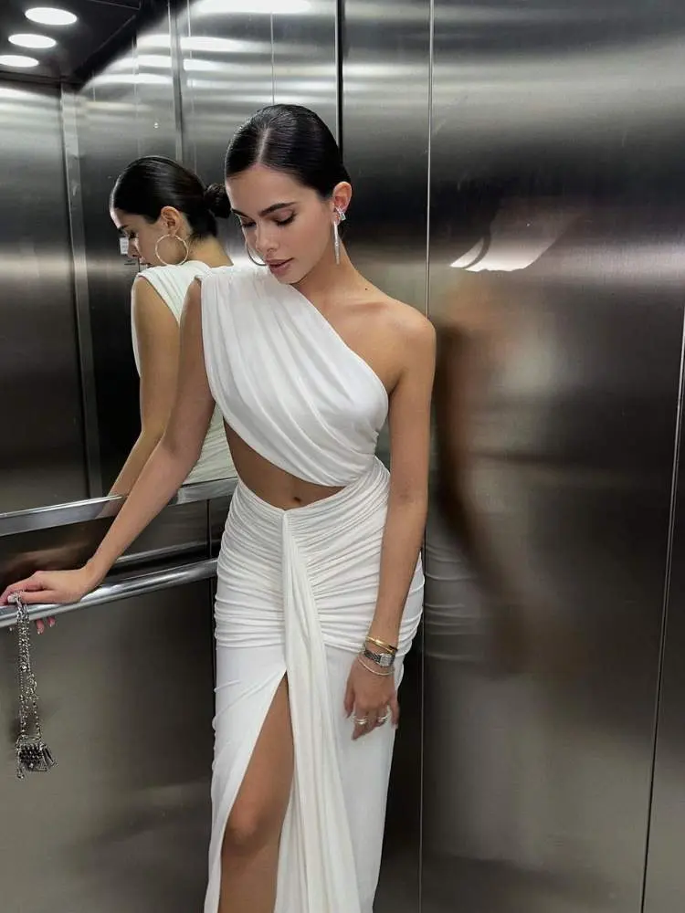 Mulher usa vestido branco com recortes como sugestão de roupa para ano novo na praia
