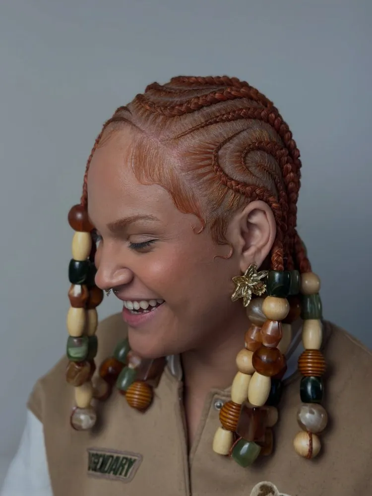 Mulher ruiva com tranças nagô com muitas miçangas grandes 