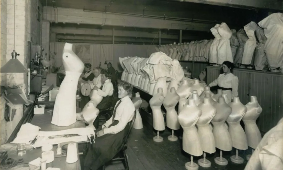 Foto em preto e branco de trabalhadoras em um fábrica de espatilho, no início do século XX Trabalhadoras em um fábrica de espatilho chamada Kalamazoo Corset Company, 1912, sendo um exemplo da moda e cidadania feminina.