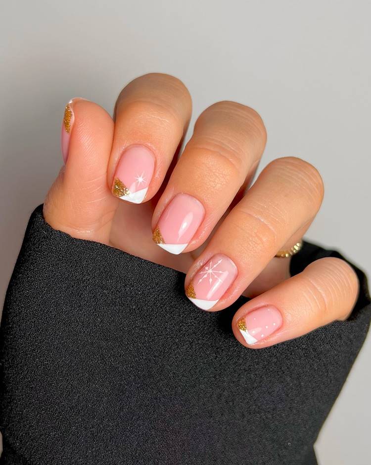 Mão com unhas decoradas para o Ano Novo, nas cores dourado, branco e desenho de floco de neve