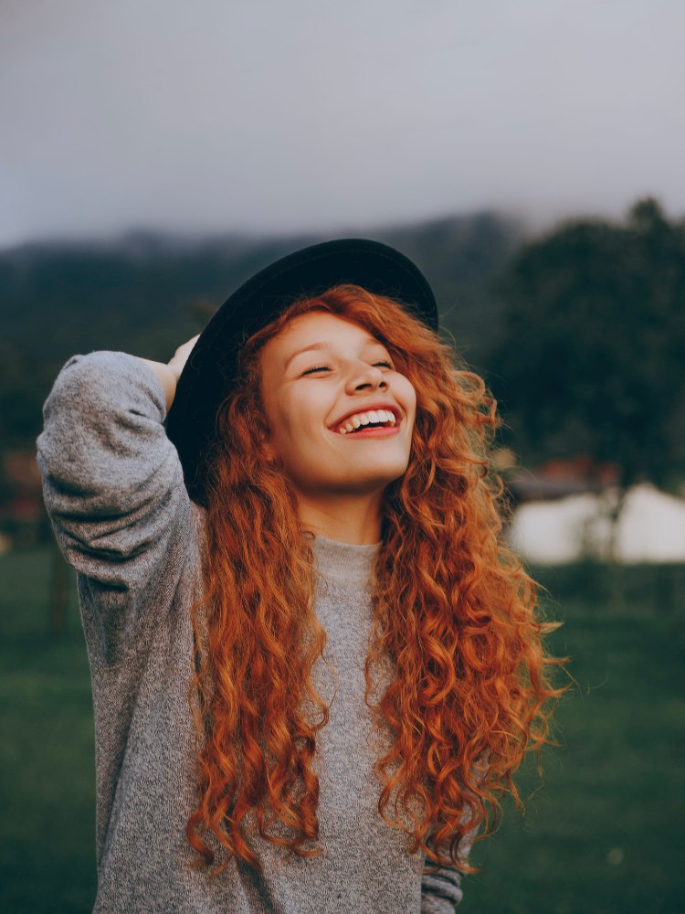 Mulher ruiva sorrindo para post sobre legendas para fotos sorrindo