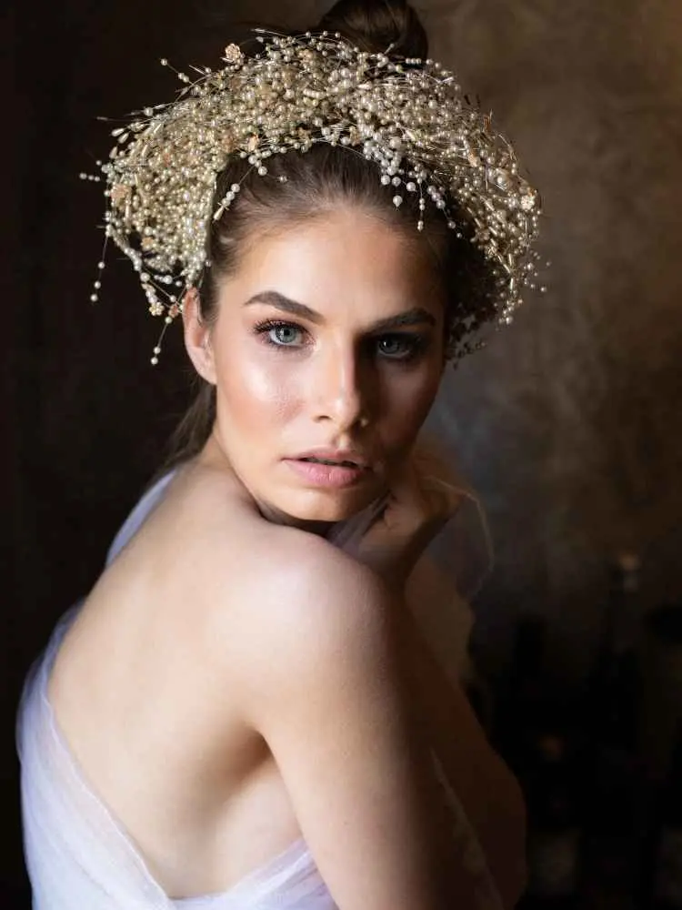Mulher com mais de 40 anos em ensaio fotográfico, usando vestido e coroa de pérolas 