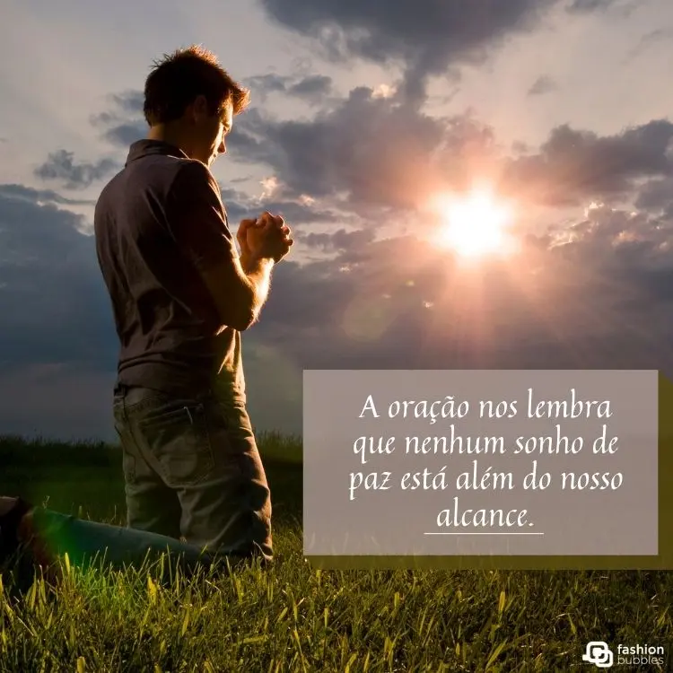 Homem ajoelhado em oração sobre a grama ao pôr do sol, com raios de luz entre nuvens. A frase “A oração nos lembra que nenhum sonho de paz está além do nosso alcance” aparece destacada em um fundo transparente.