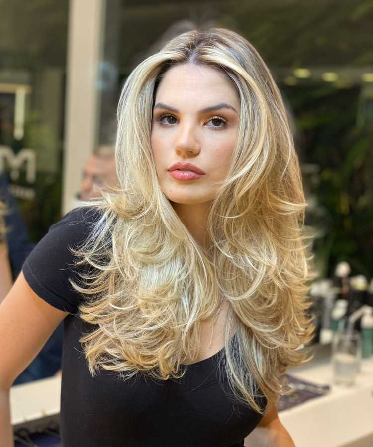 A imagem mostra uma pessoa com um corte de cabelo longo e repicado, em camadas. As camadas criam volume e movimento, com as pontas viradas para fora, proporcionando um visual dinâmico e moderno. Esse estilo é frequentemente chamado de "corte em camadas repicadas" ou "corte em camadas longas", popular por sua versatilidade e por adicionar textura ao cabelo.


