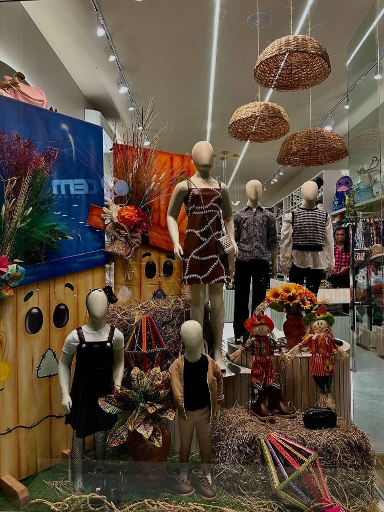 Vitrine com manequins com roupa marrom, painéis de espantalho e feno 